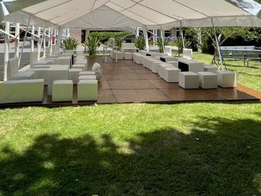 Sillones y pufs de living armados bajo una carpa para un evento