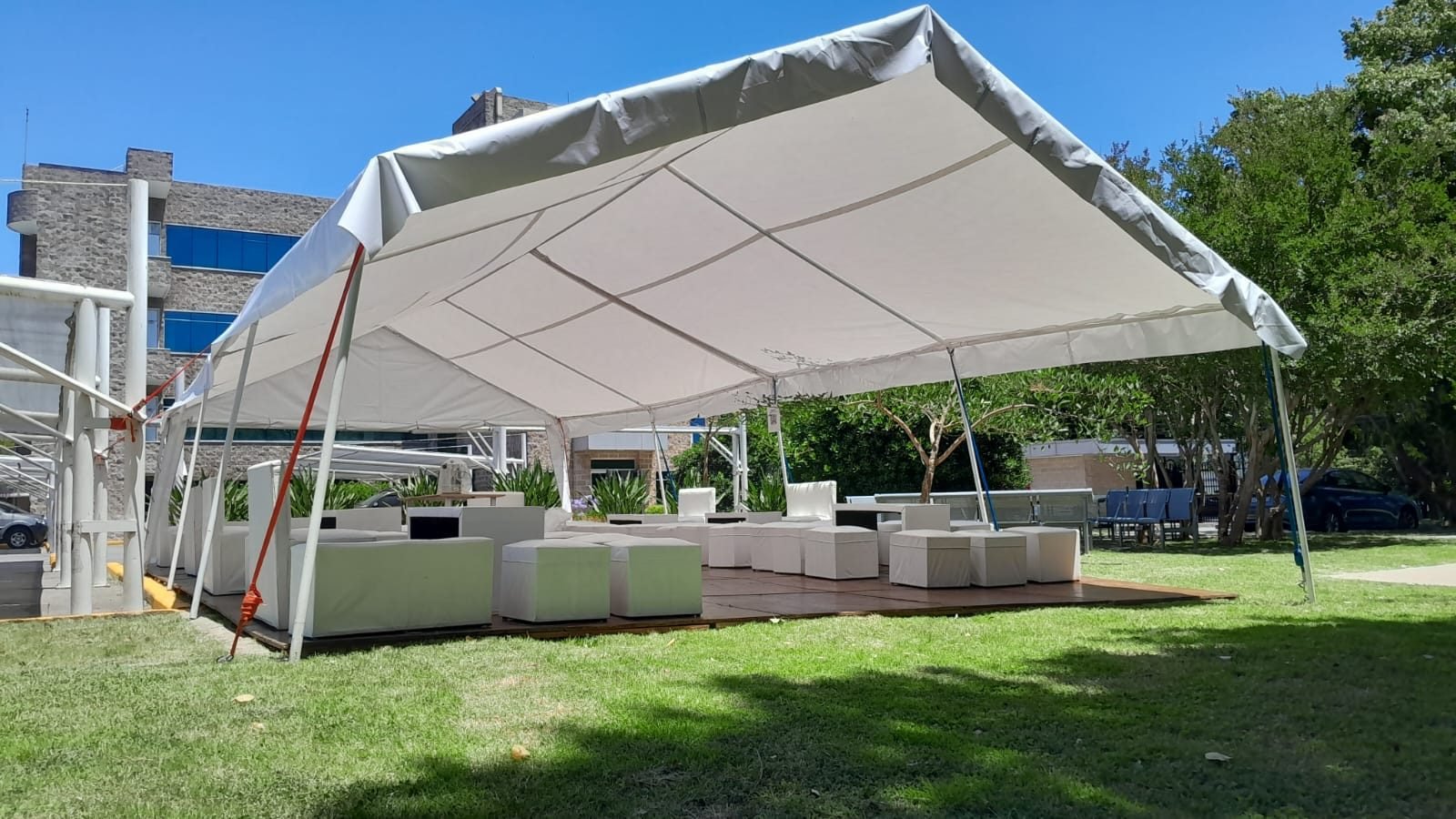 Carpa armada para un evento al atardecer, con luces cálidas y mesas puestas