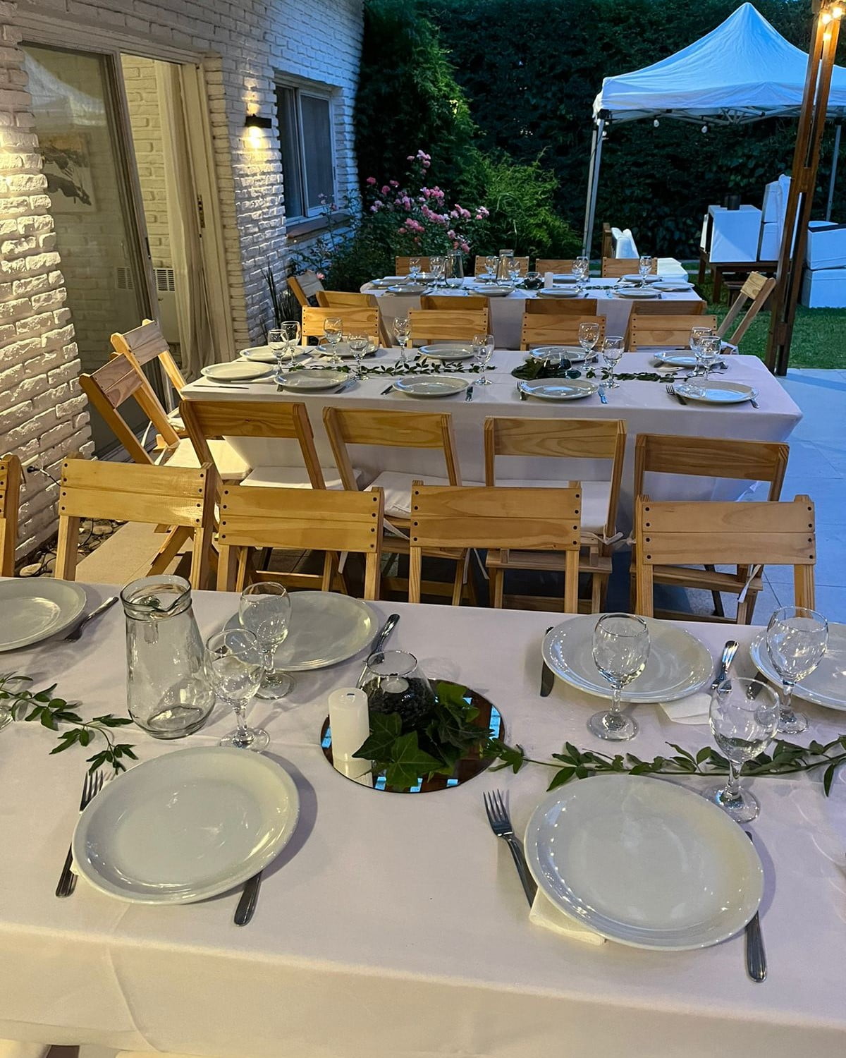 Mesa con vajilla de porcelana, sillas de madera y manteleria blanca