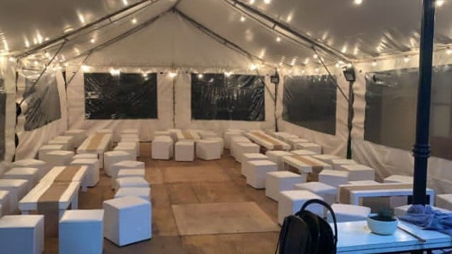 Interior de una carpa, iluminada con guirnalda de focos y puff para 70 personas