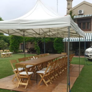 Gazebo blanco de 6 por 3 metros sin laterales. mesa rectangular de madera para 10 personas con sillas de madera con almohadas. Piso de madera sobre pasto